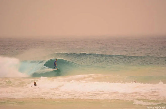 Imagem de mar com ondas e homem surfando.